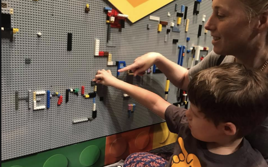 Woman and kids looking at a Lego mural