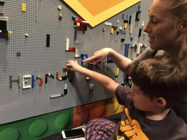 Woman and kids looking at a Lego mural