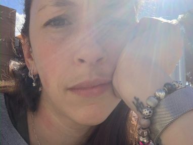 Mother looking at the camera, squinting because the sun is in her eyes.