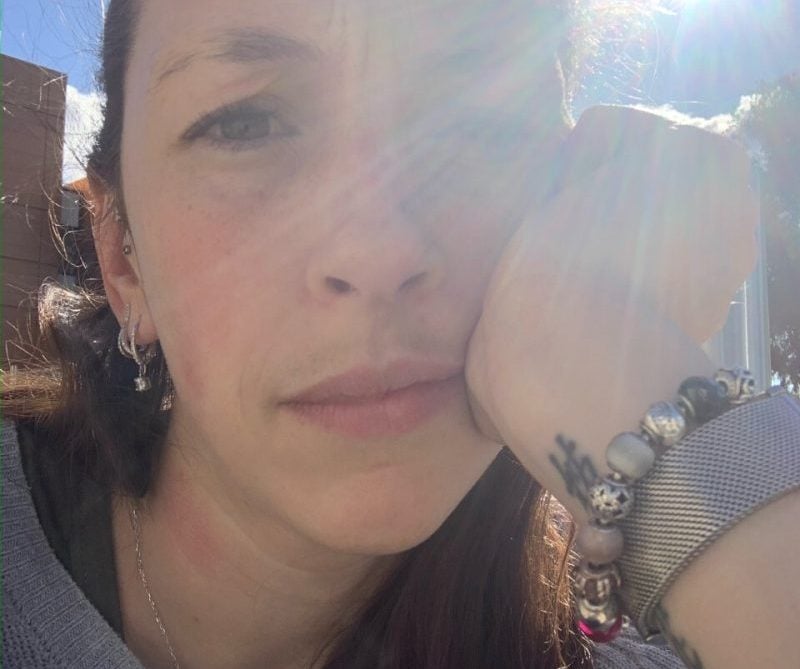 Mother looking at the camera, squinting because the sun is in her eyes.