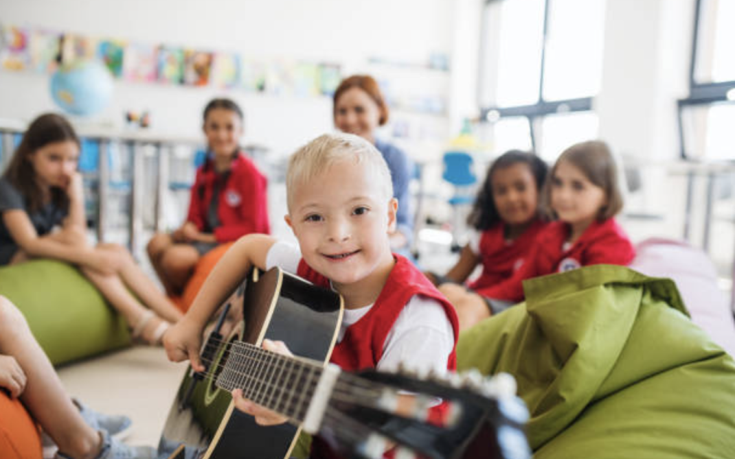Kids in a class room holding a guitar