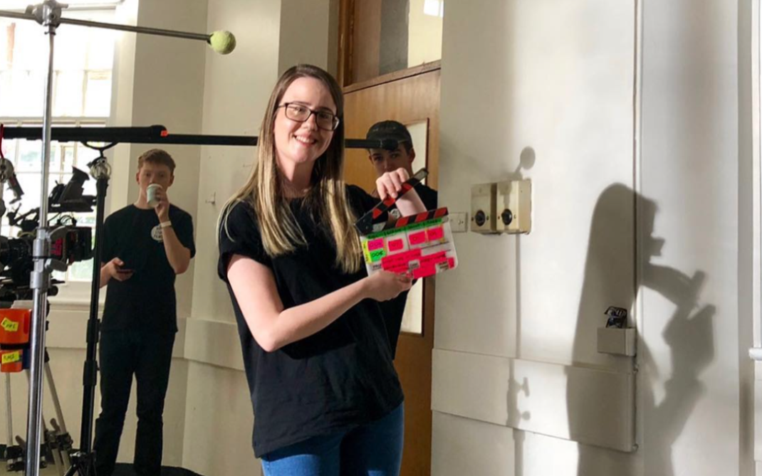 A woman holding a box in a room with other people behind her.