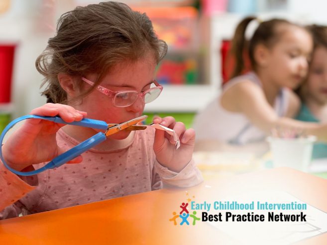 young girl with down syndrome at preschool cutting paper at a table