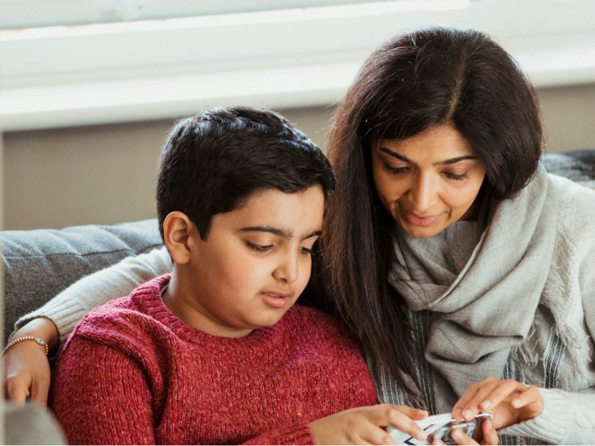 Mother and son sitting together looking at a tablet.