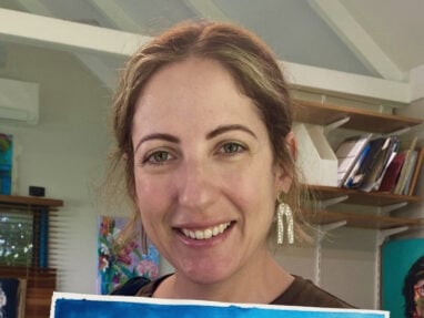 Natasha holding one of her artworks, a painting of a turtle