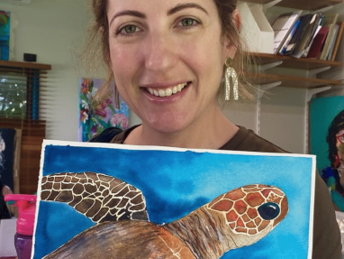 Natasha holding one of her artworks, a painting of a turtle