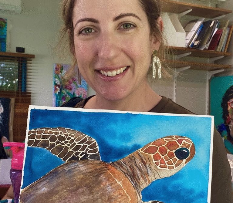 Natasha holding one of her artworks, a painting of a turtle