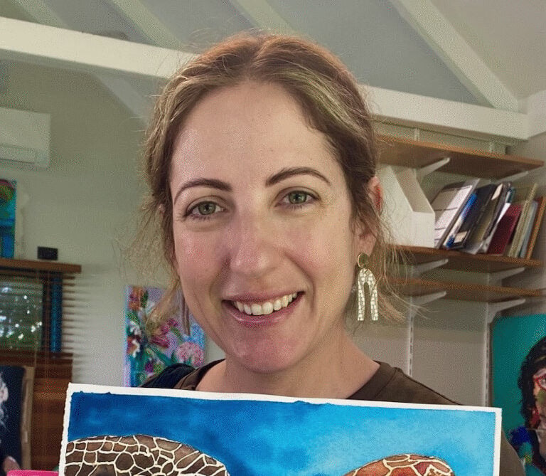 Natasha holding one of her artworks, a painting of a turtle