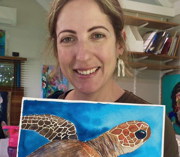 Natasha holding one of her artworks, a painting of a turtle