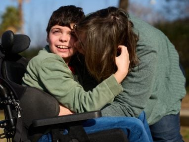 mother hugging son in wheelchair