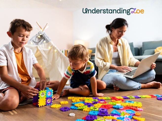 Female using computer while 2 male children are playing on the floor.